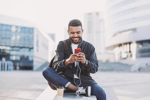 Student man using mobile phone on a city street. Freelance work, communication, business concept